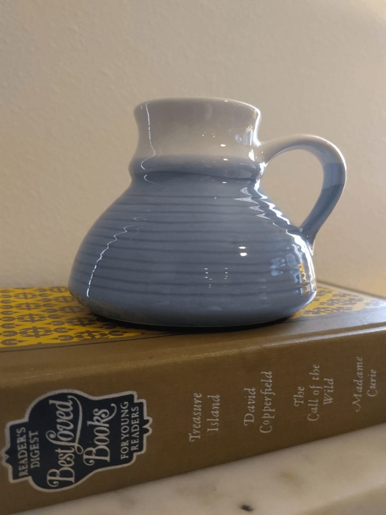 Blue ceramic jug atop golden hardcover