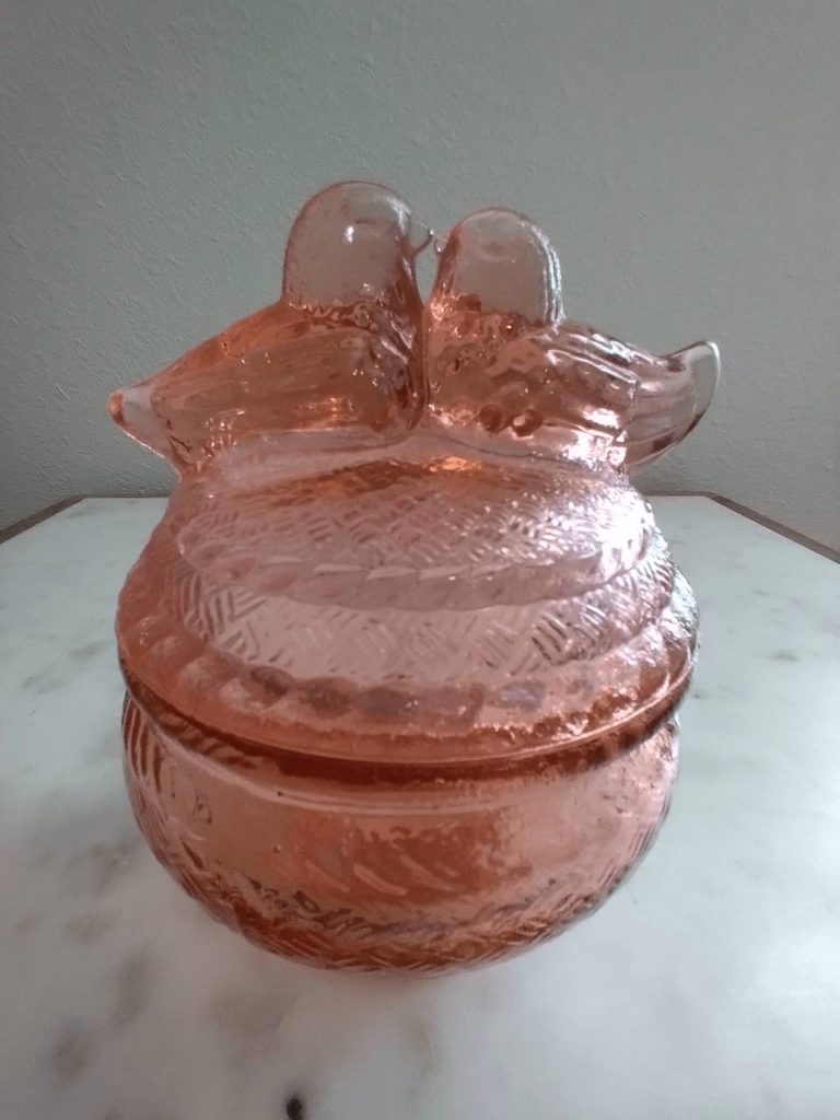Pink glass container with bird-shaped lid.